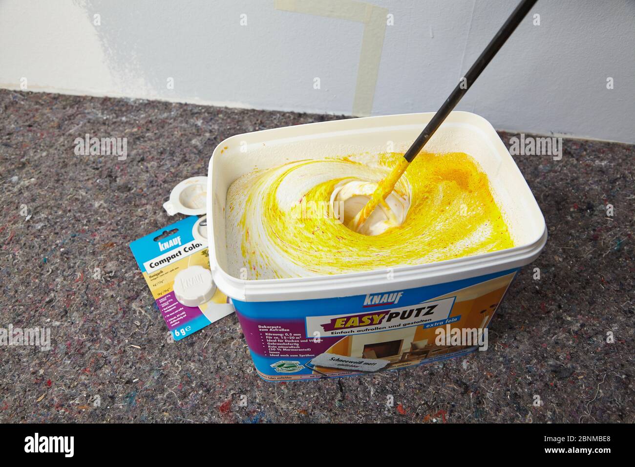 DIY wall design 03, step-by-step do-it-yourself production, various colored areas with wall paint and roller plaster, gray and yellow, step 3: stirring up the plaster and tinting with color pigments Stock Photo