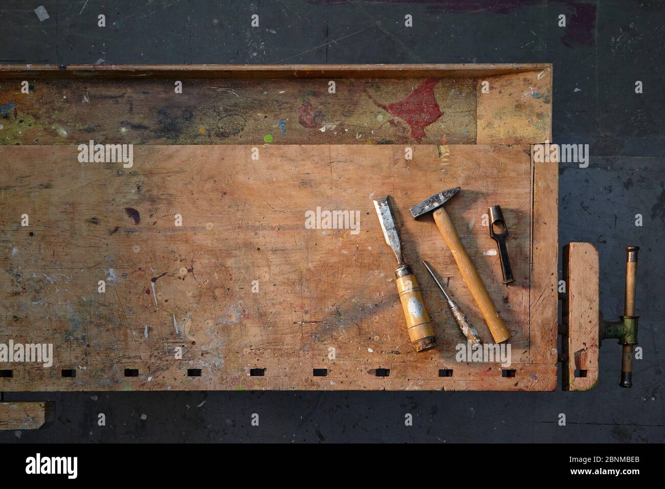 old wooden workbench, graphically photographed from above, dark gray workshop floor, with few tools, tidy, variant 1 of 5 Stock Photo