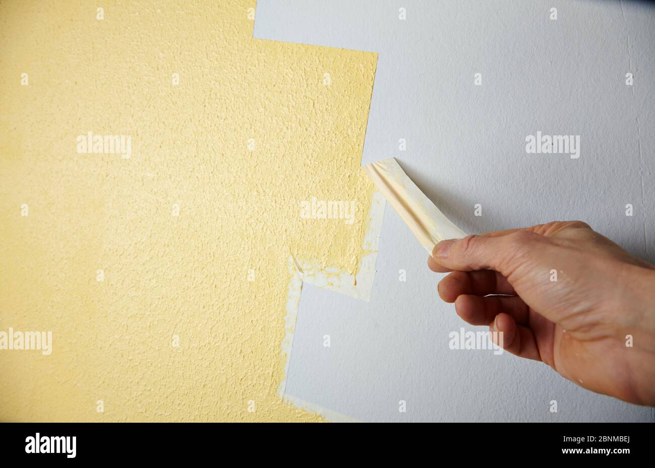 DIY wall design 03, step-by-step do-it-yourself production, various colored areas with wall paint and roller plaster, gray and yellow, Step 5: Peel off the masking tape when the paint is still slightly damp Stock Photo