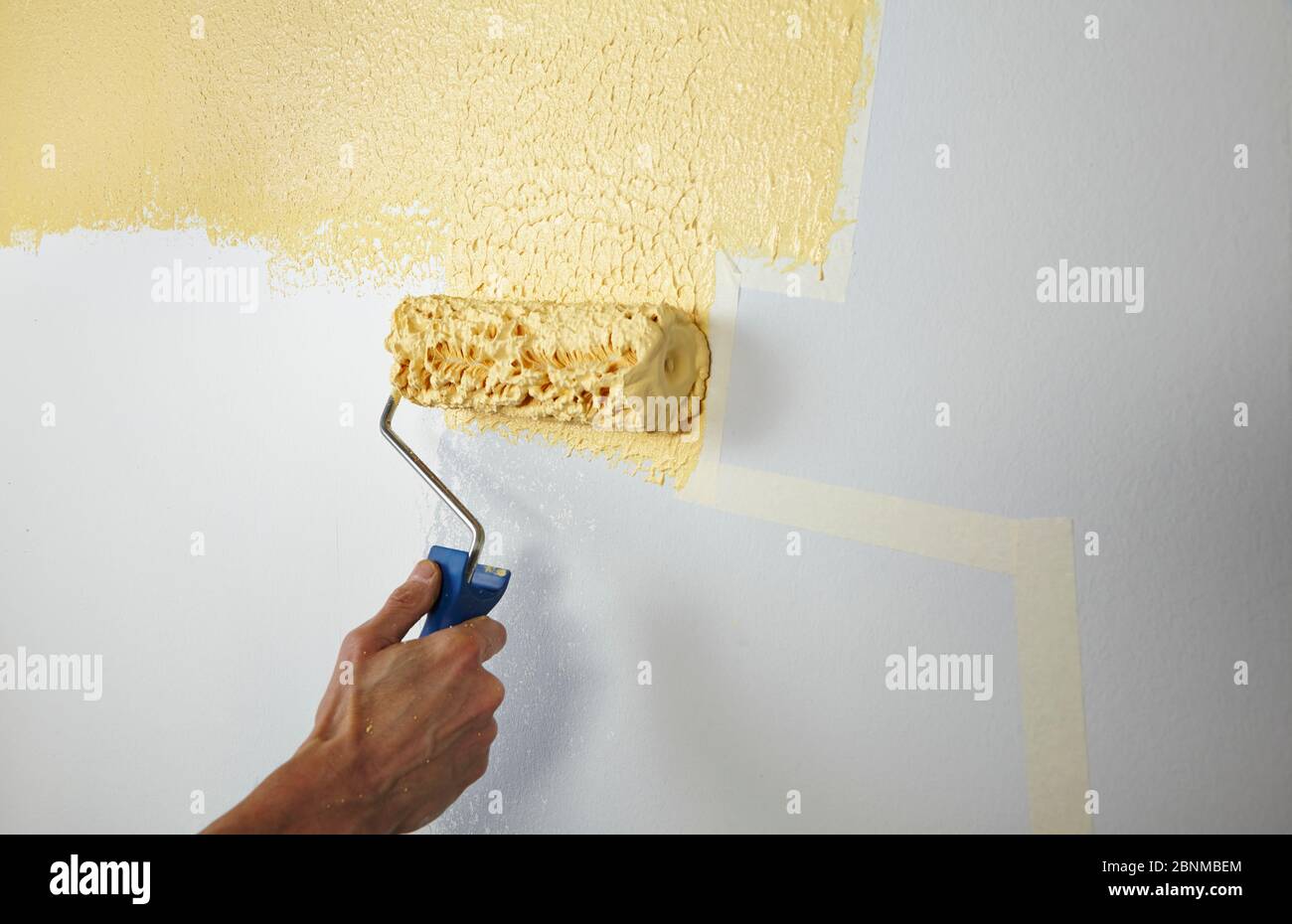 DIY wall design 03, step-by-step do-it-yourself production, various colored areas with wall paint and roller plaster, gray and yellow, step 4: painting the taped areas with roller plaster and paint roller Stock Photo