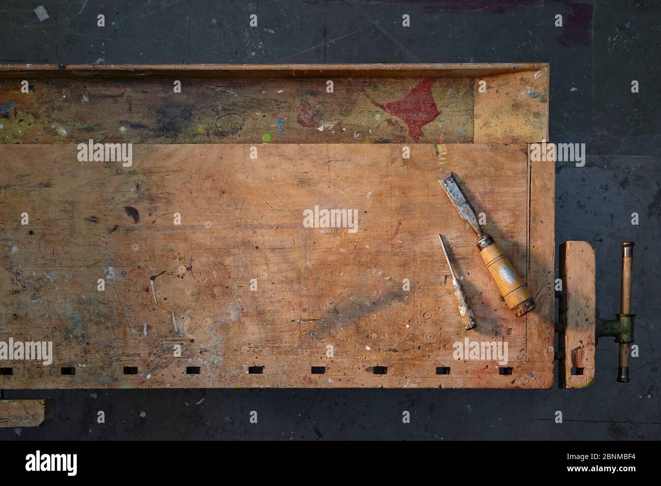 old wooden workbench, graphically photographed from above, dark gray workshop floor, with few tools, tidy, variant 4 of 5 Stock Photo