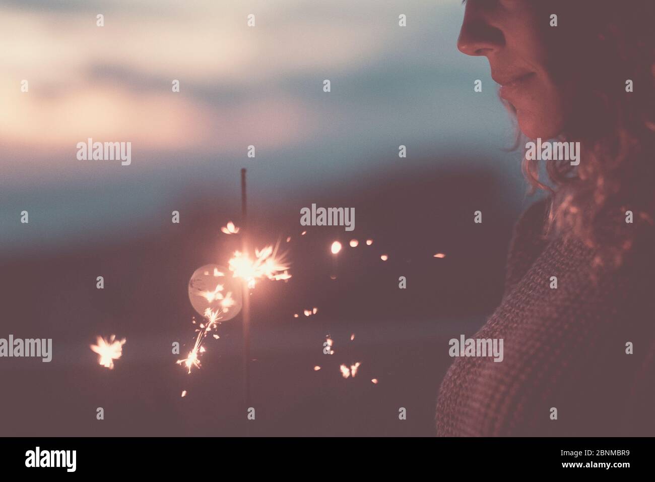 Young woman looks at sparkler Stock Photo