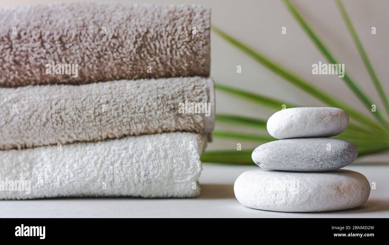 https://c8.alamy.com/comp/2BNMD2W/three-grey-roundstones-and-bath-towels-on-white-background-with-green-leaves-spa-stones-zen-like-concept-2BNMD2W.jpg
