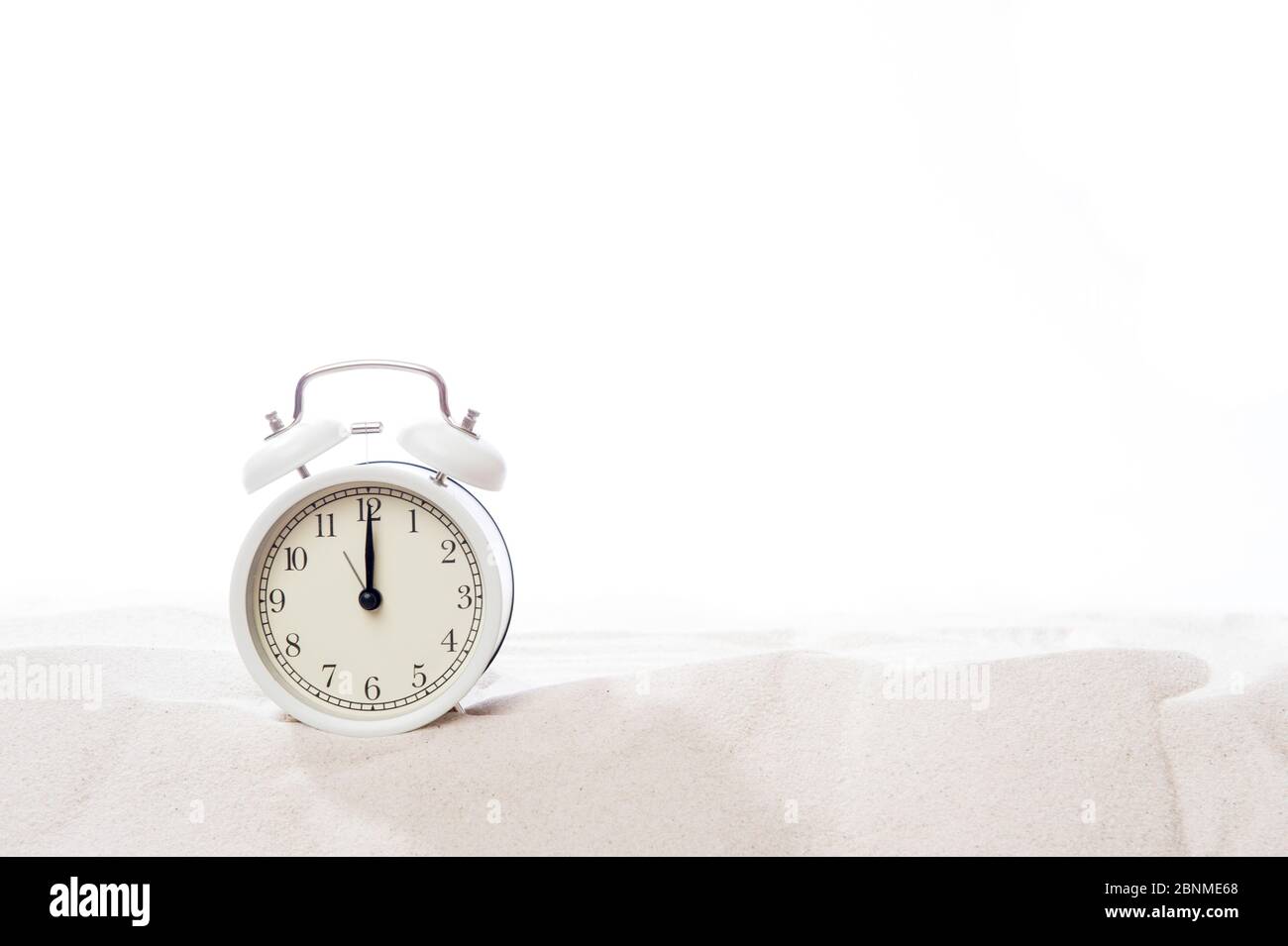 Alarm clock in sand on beach. Vacation time concept Stock Photo