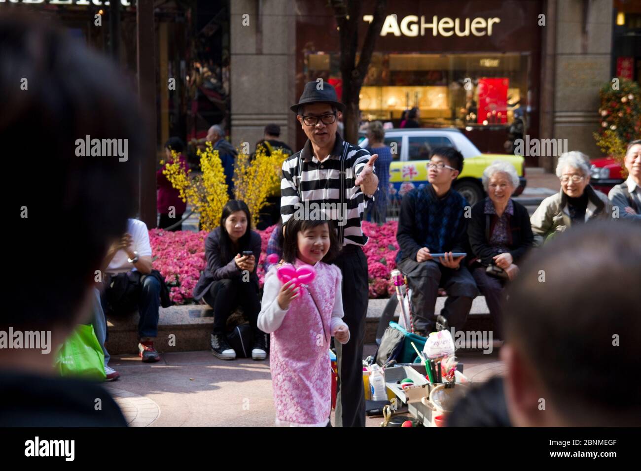 Street balloon artist with little girl in pink in Hong Kong Stock Photo
