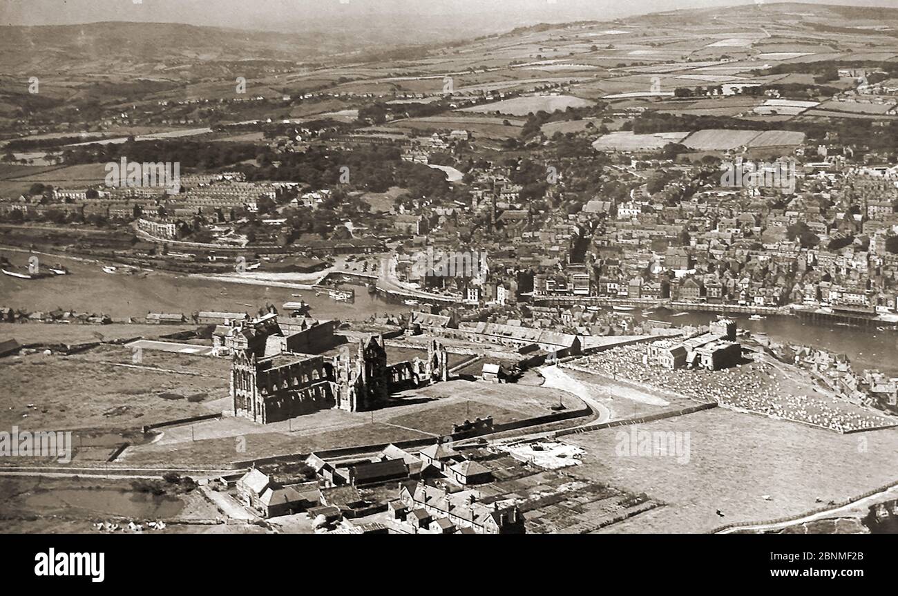 An old Whitby photograph  (circa 1940's?) from the air showing the town before redevelopment of the Dock End and railway coal yard areas where the Co-op store was eventually built. Also shown is the second Whitby Abbey monks fish pond (bottom left) that has now been filled in. Erosion of the cliffs, (right) had now occurred with much of the fields falling into the sea. The 'market' cross on the present Abbey Plain is seen here with the abbey grounds. Stock Photo