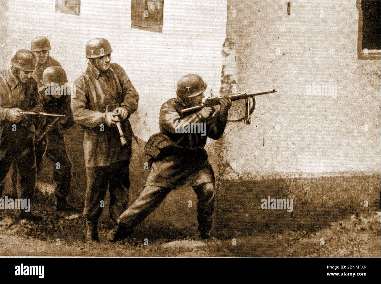 WWII -   Battle of Greece aka Operation Marita or Unternehmen Marita  - A printed image from 1941 showing Nazi German paratroopers in action in Corinth, Greece. One soldier shoots around the corner of a building whilst the man behind gets ready with a hand grenade.Operation Marita followed the  Italian invasion in October 1940. It is sometimes known as the Greco-Italian War. Stock Photo