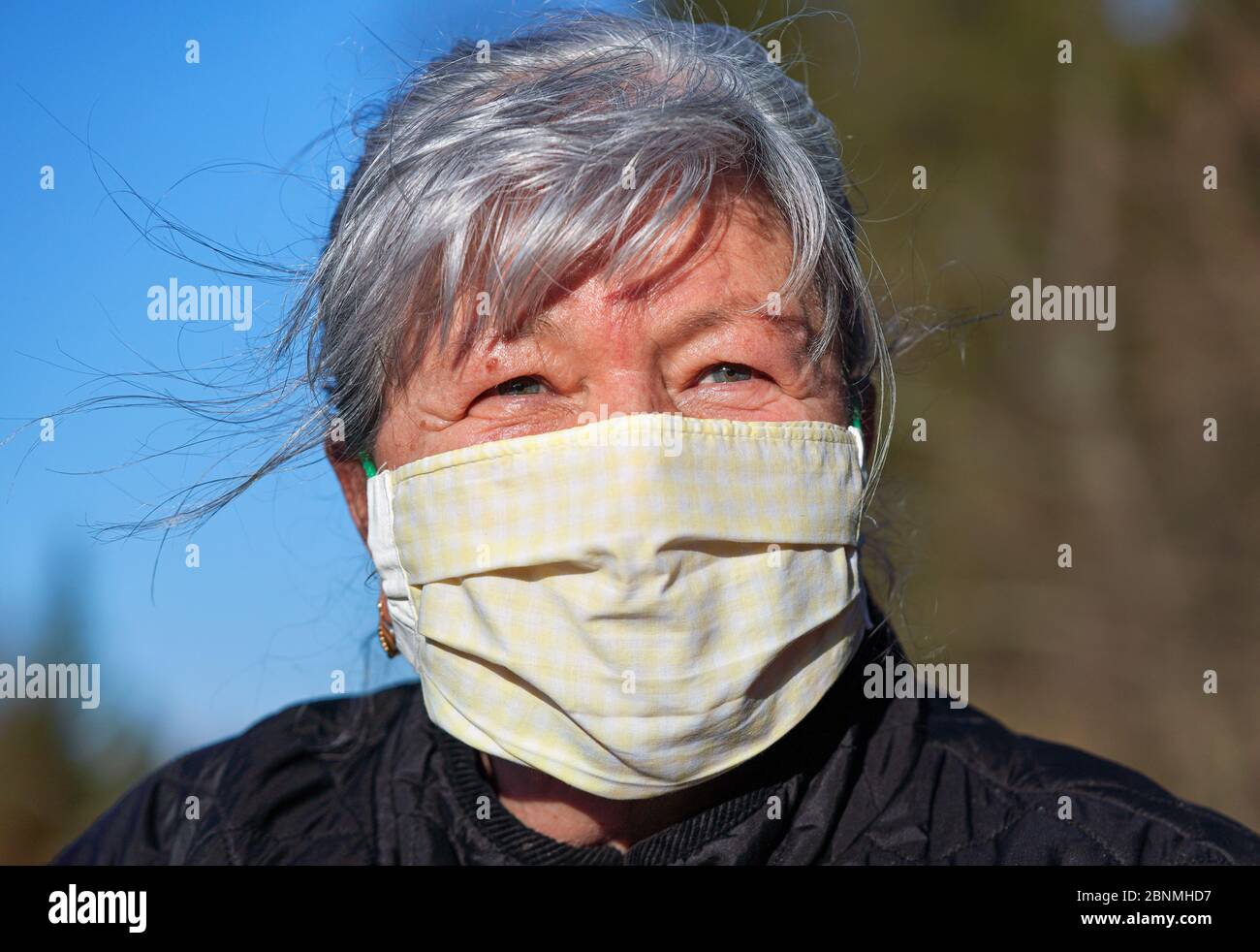Elderly senior woman with gray hair wearing home made cloth face mouth nose virus mask outside. Can be used during coronavirus covid-19 outbreak preve Stock Photo