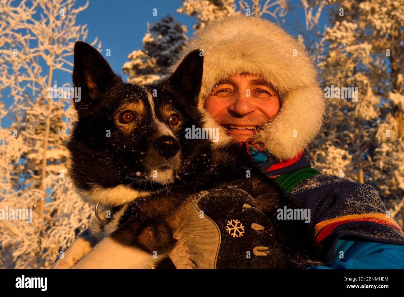 Nils-Torbjörn Nutti, owner and operator at Nutti Sami Siida, with domestic husky dog, during snowmobile trip into the wilderness, Jukkasjarvi, Lapland Stock Photo