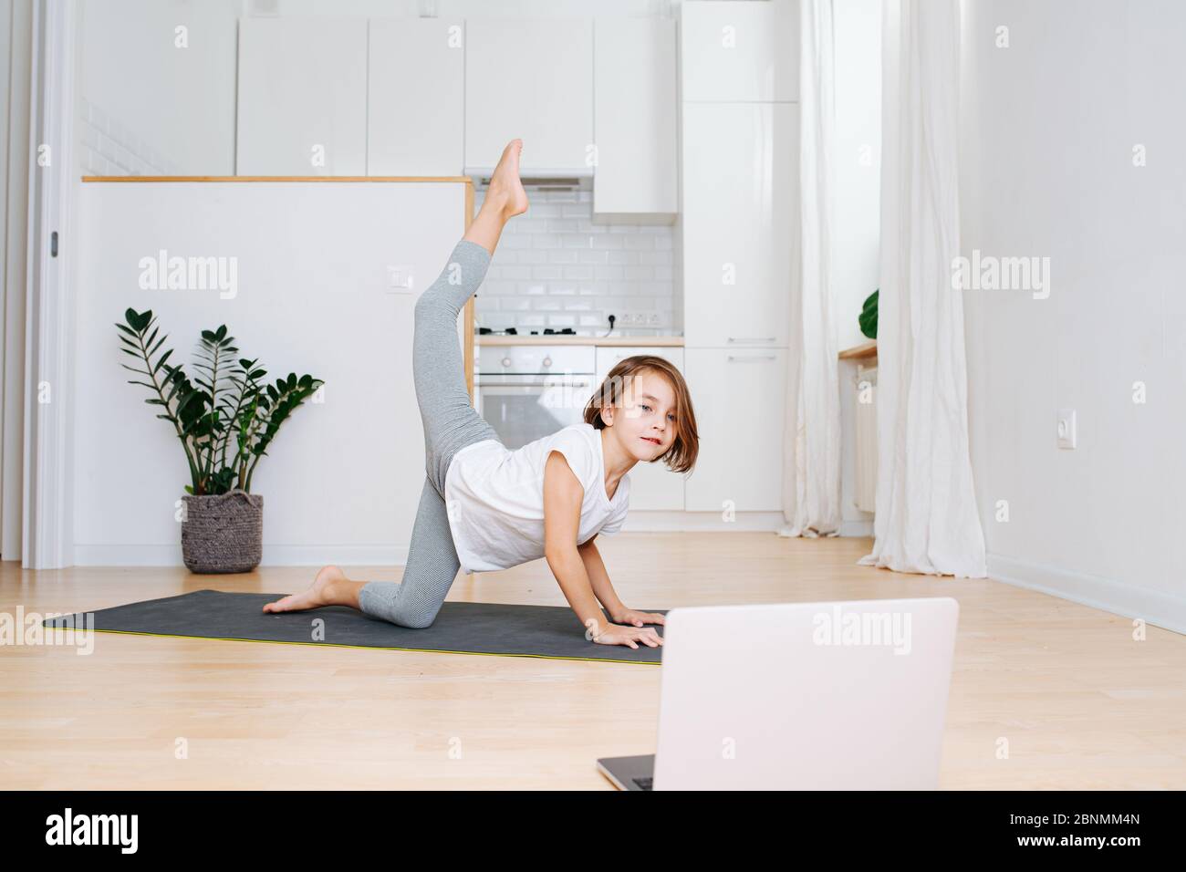 Little school age girl doing gymnastics at home in isolation Stock Photo