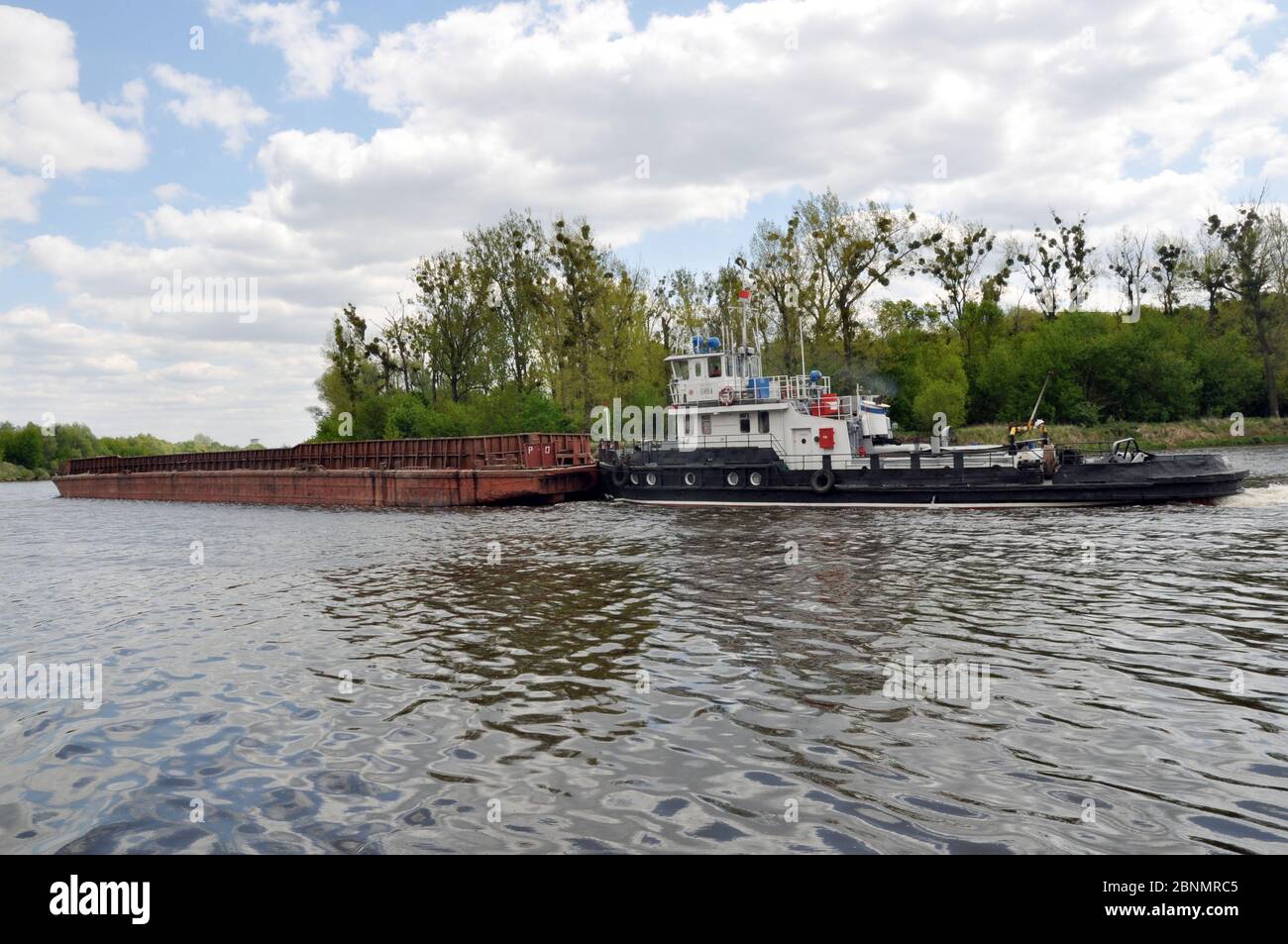 Movement of a tugboat with a barge along the Pripyat River. Stock Photo