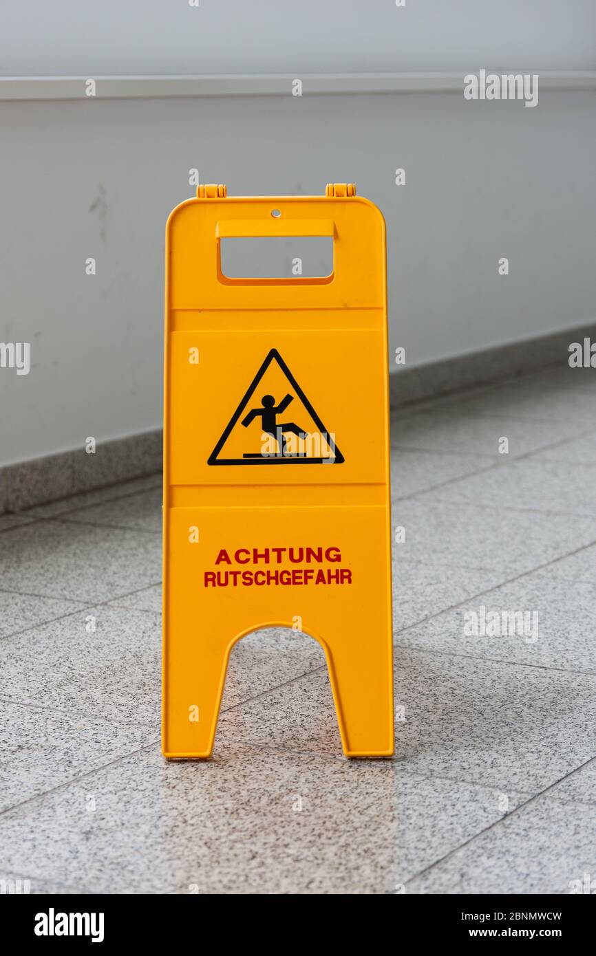 Caution wet floor or cleaning in progress. A yellow sign warns of danger. Stock Photo