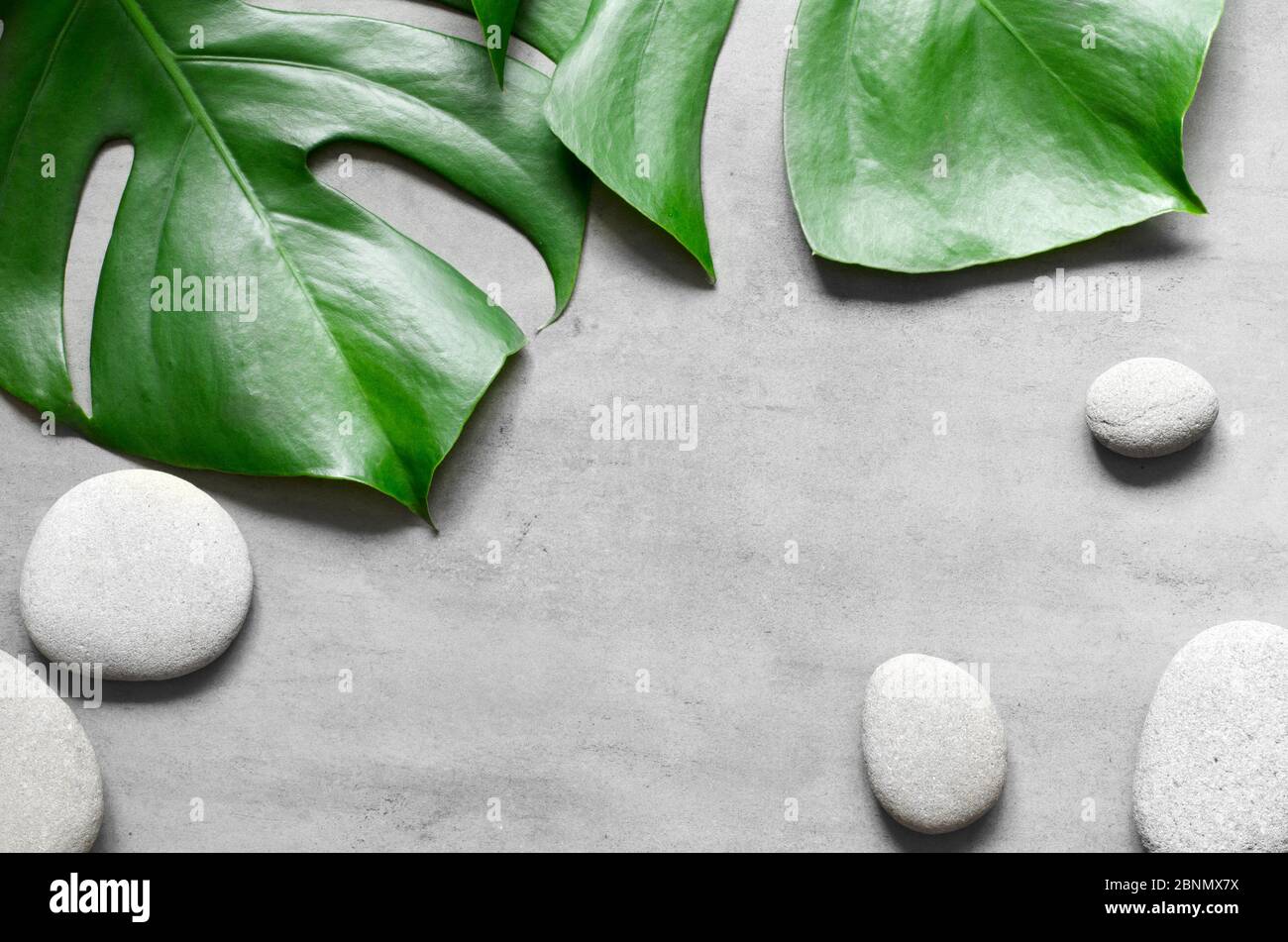 Flat lay composition with spa stones, palm leaves on grey background ...