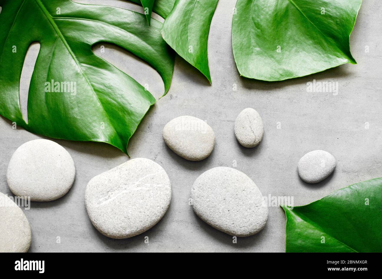 Flat lay composition with spa stones, palm leaves on grey background ...