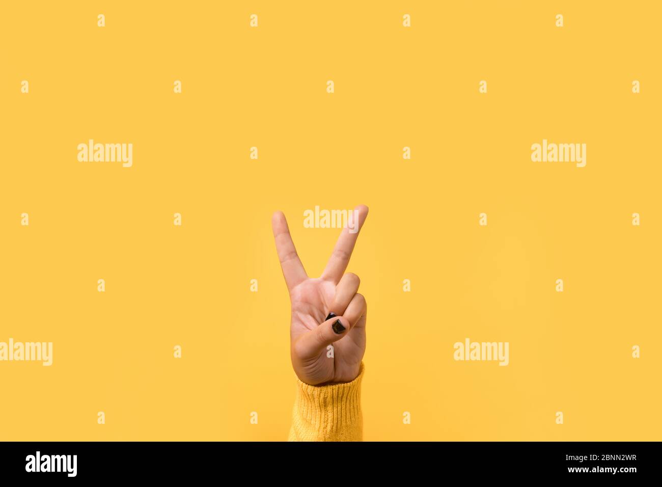Hand gesture V sign for victory or peace sign over yellow background ...