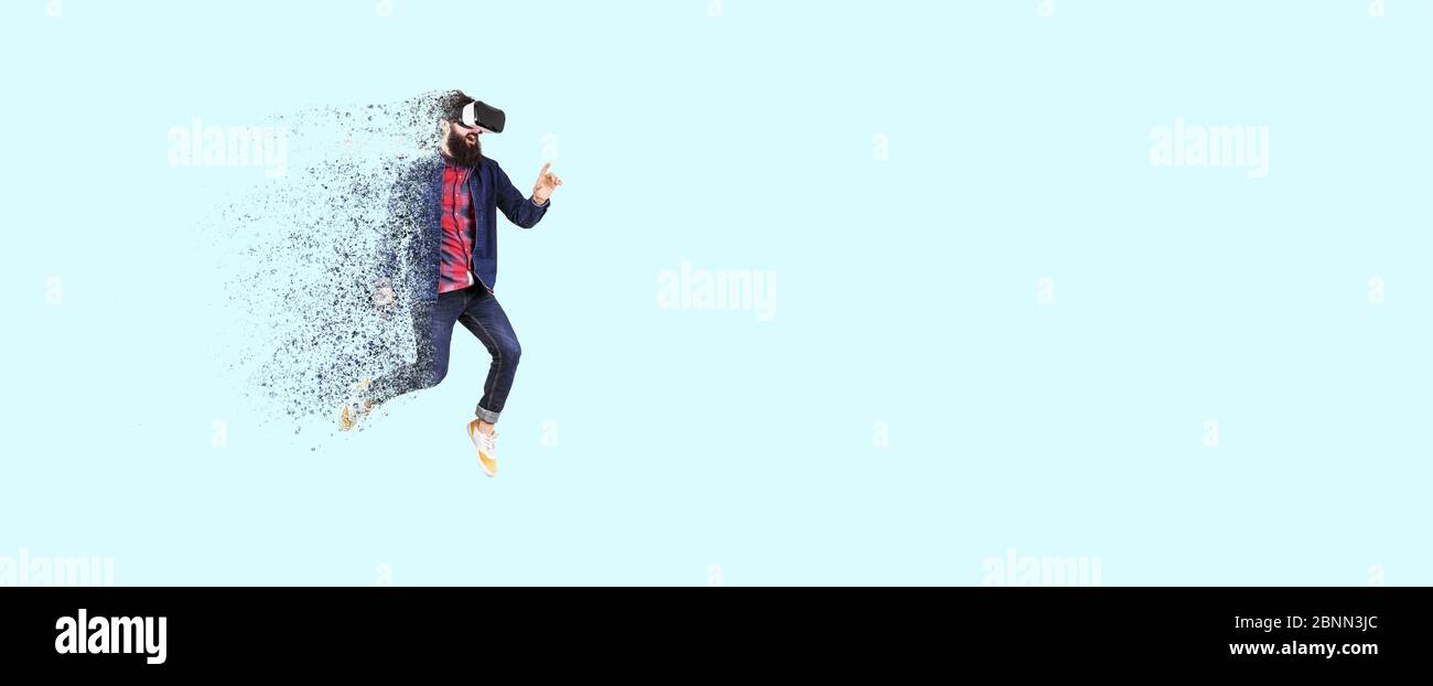 Full length portrait of a jumping bearded hipster in glasses of virtual reality, man dispersing and disintegrating into particles,concept of new techn Stock Photo