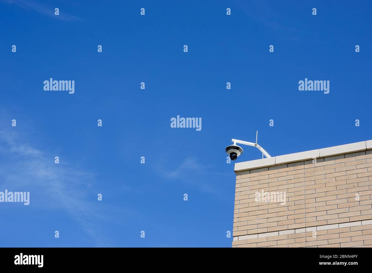 A security camera on a building overlooking a sidewalk with copy space