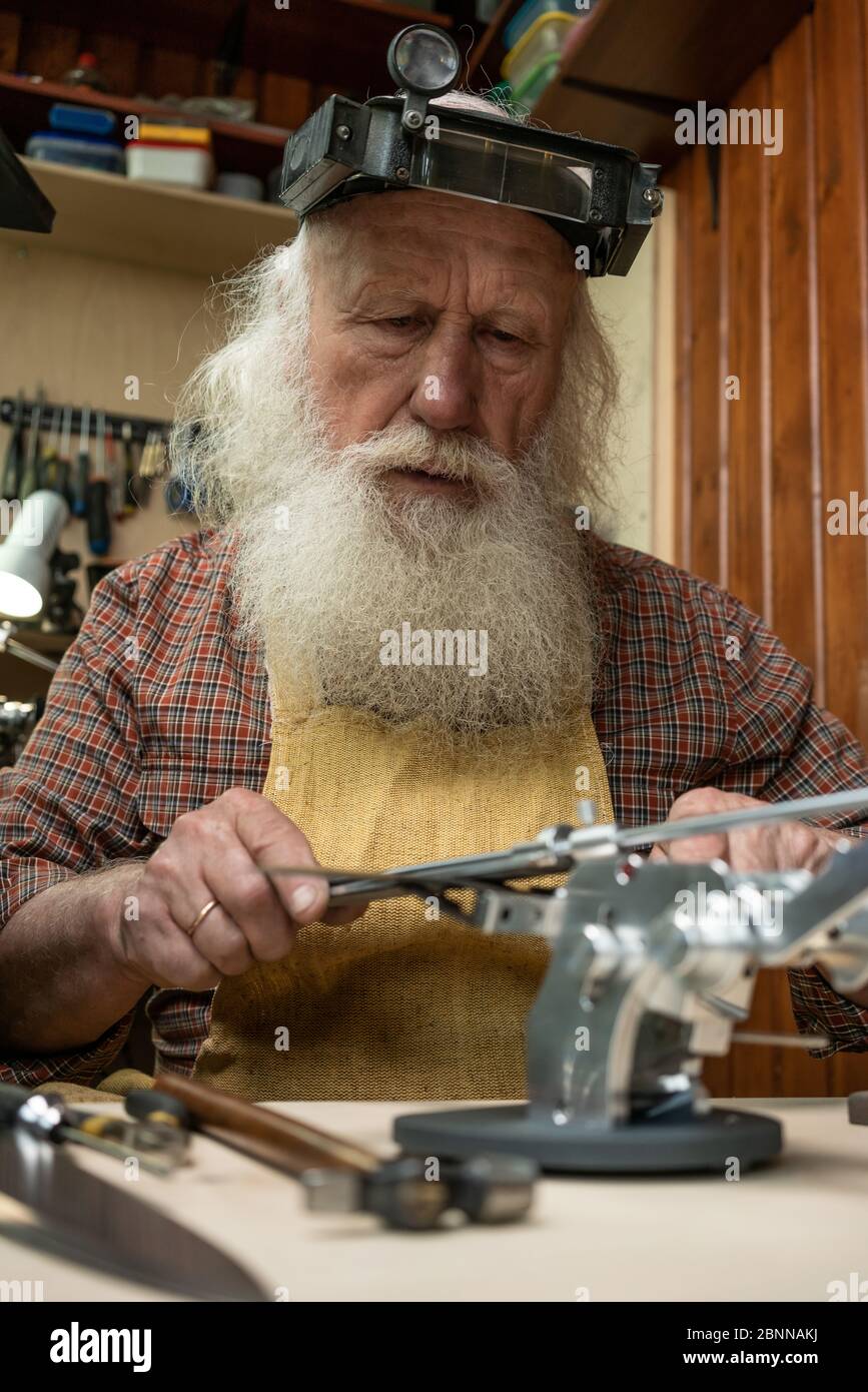 Male profession. Master knife sharpener working in the Studio Stock Photo