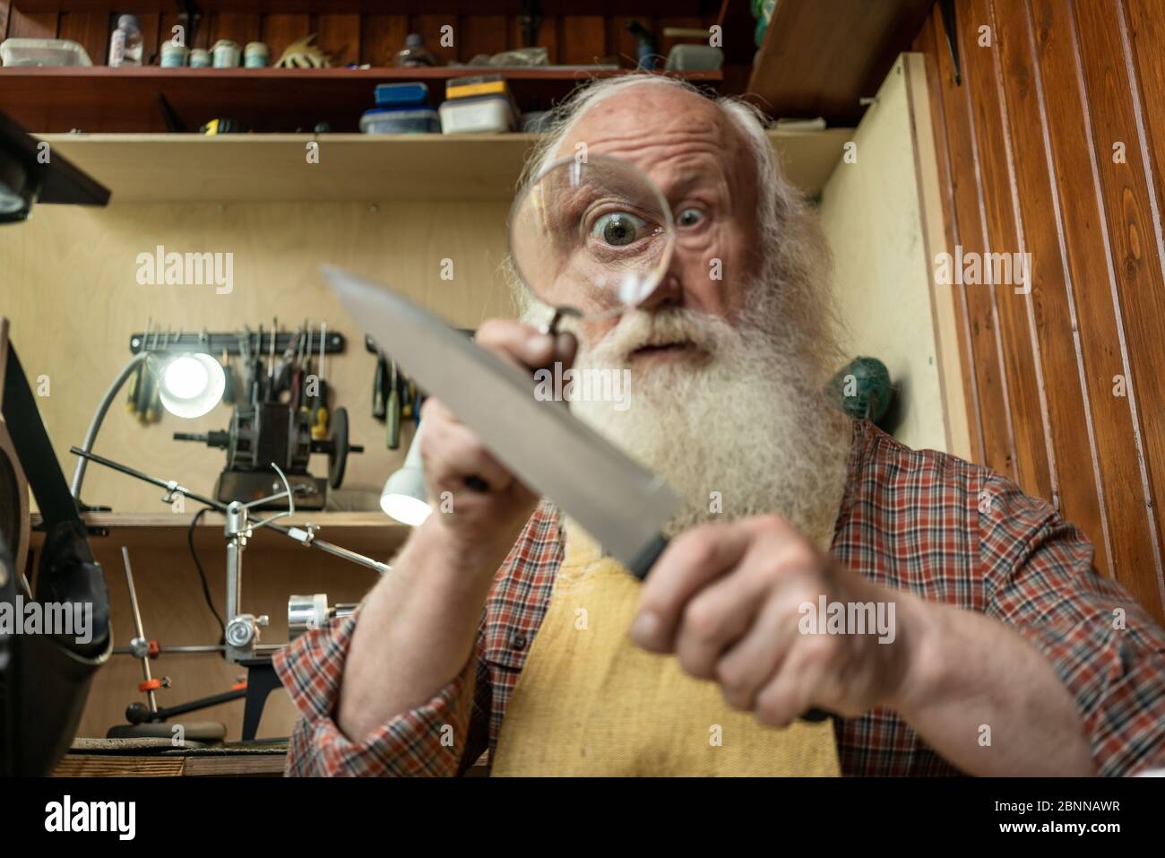 Senior old man looking through zoom magnifying glass. Funny elder