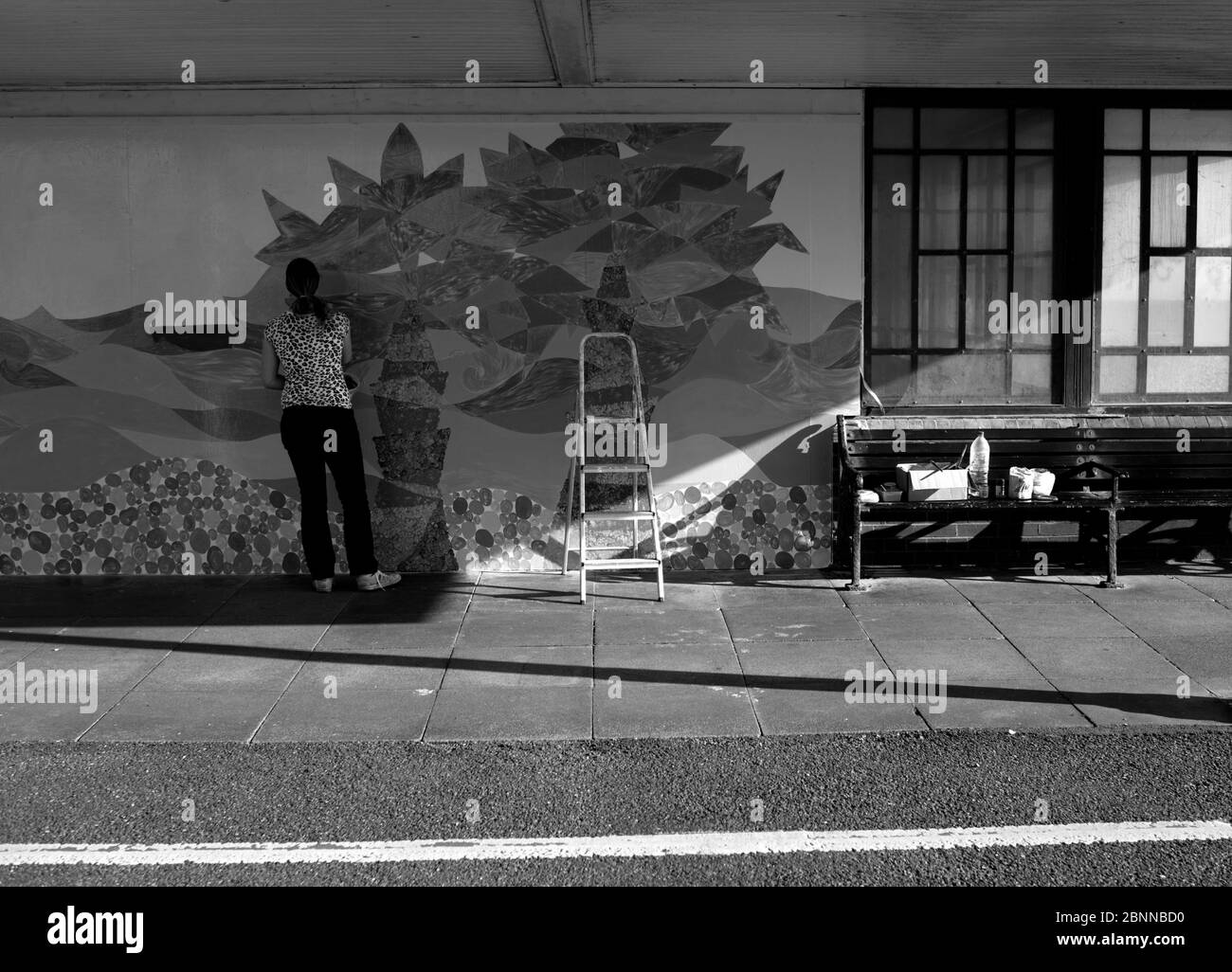 WORTHING, ENGLAND. MURAL PAINTING ARTIST AT WORK PAINTING MURAL ON THE WALL OF