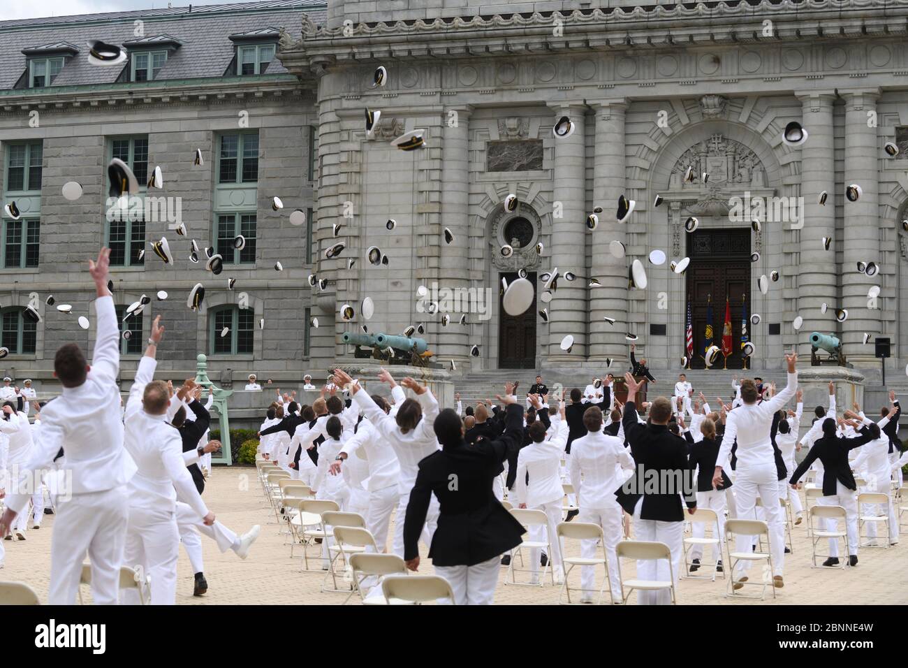 U.S Naval Academy graduates toss their hats into the air following the 2020 graduation and commissioning ceremony under COVID-19, coronavirus pandemic social distancing rules May 12, 2020 in Annapolis, Maryland. Approximately 1,000 midshipmen will graduate and be sworn-in during five events and one virtual ceremony. Stock Photo