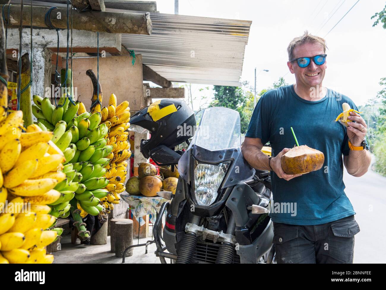 Motorbike rider enjoying local fruit, Machala, El Oro, Ecuador Stock Photo