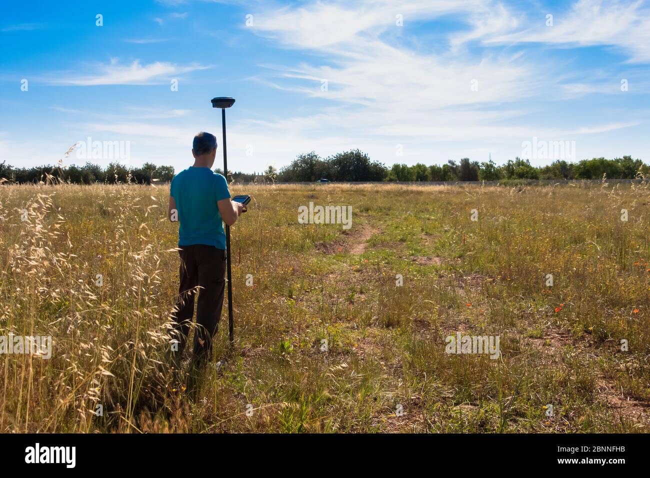 Land surveyor working in the field with a GPS instrument, taking data from the surface. Field works Stock Photo