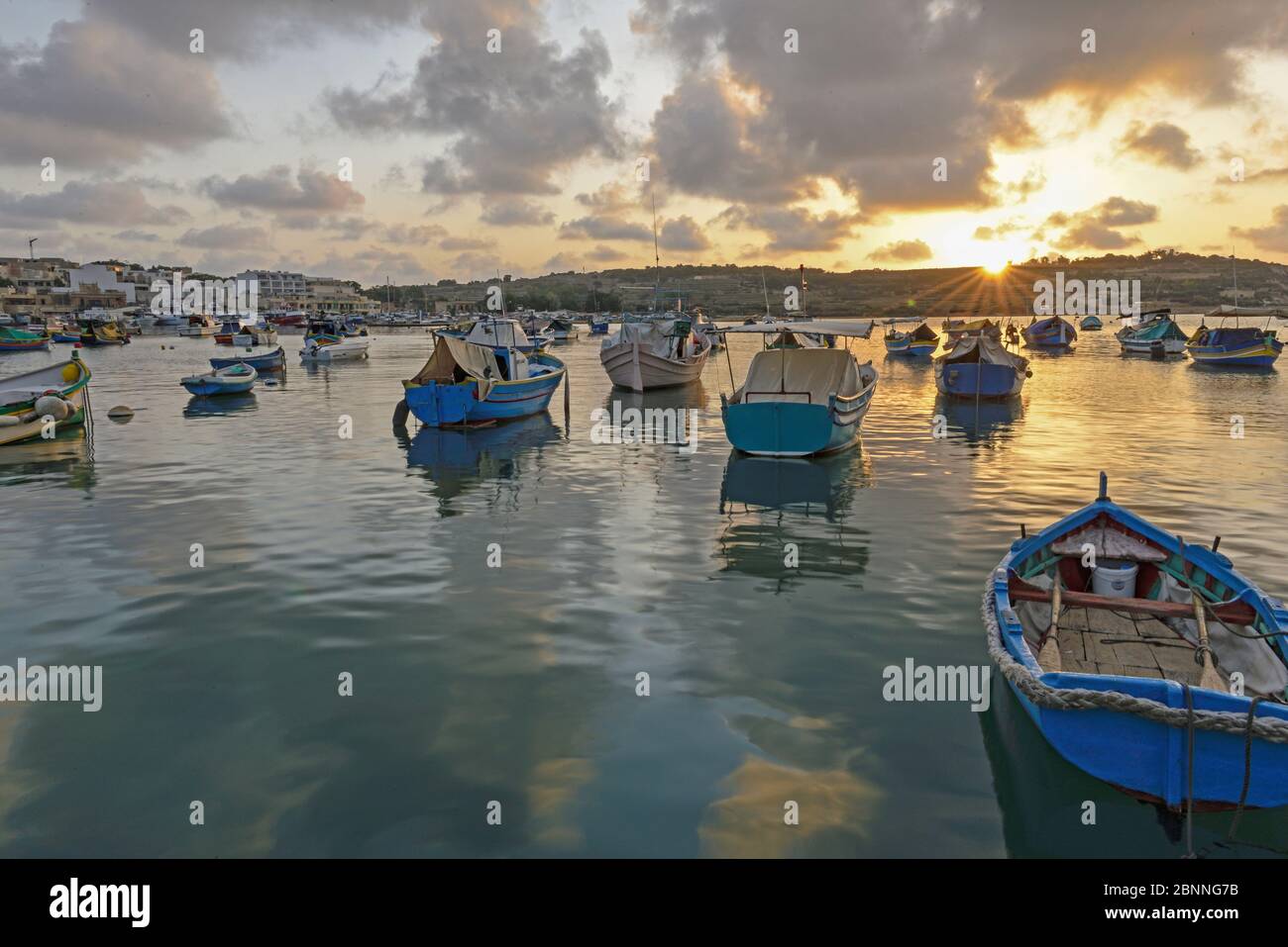 Sunrise in the fishing port of Marsaxlokk with the typical colorful fishermen in the foreground Stock Photo