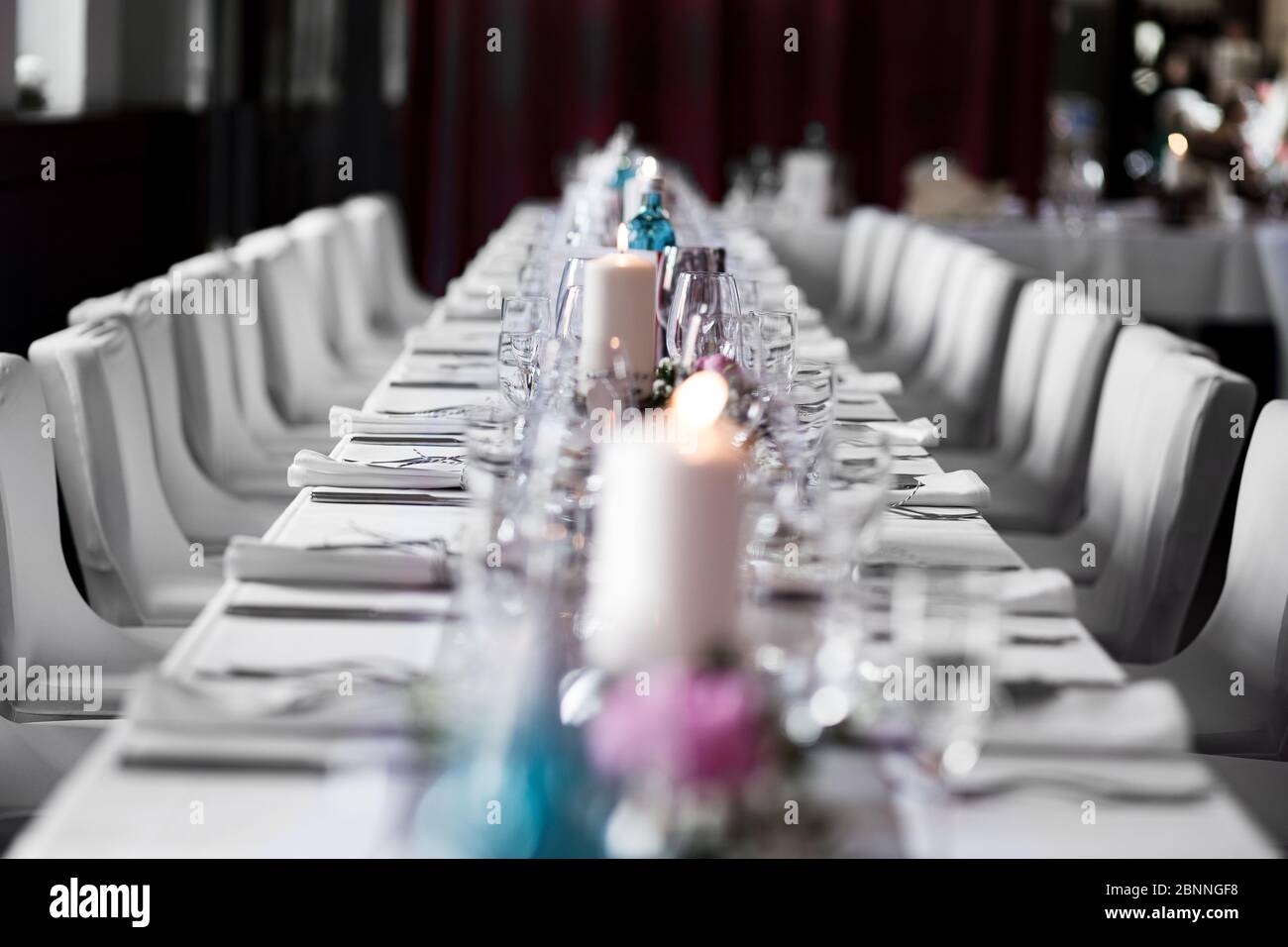 long dinner table white tablecloth candle like wedding table decoration. Event location in a restaurant. Stock Photo