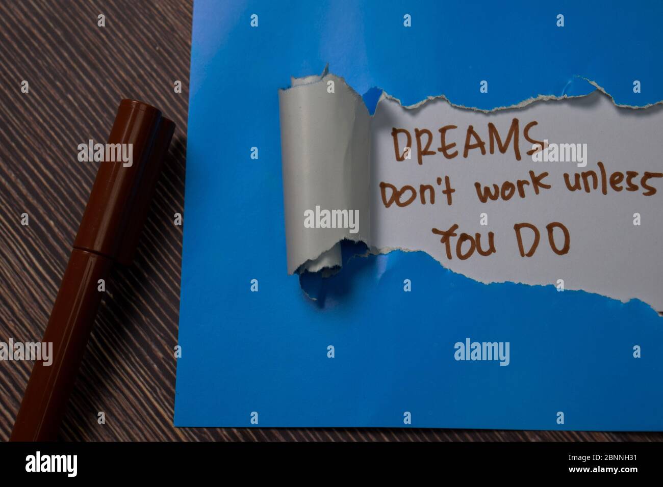 Dreams Don't Work Unless You Do Text written in torn paper. Stock Photo