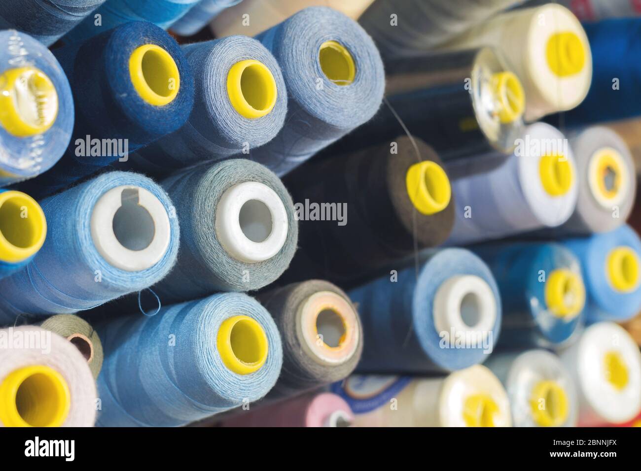 Colored thread on bobbins in a sewing workshop. Garment industry concept Stock Photo
