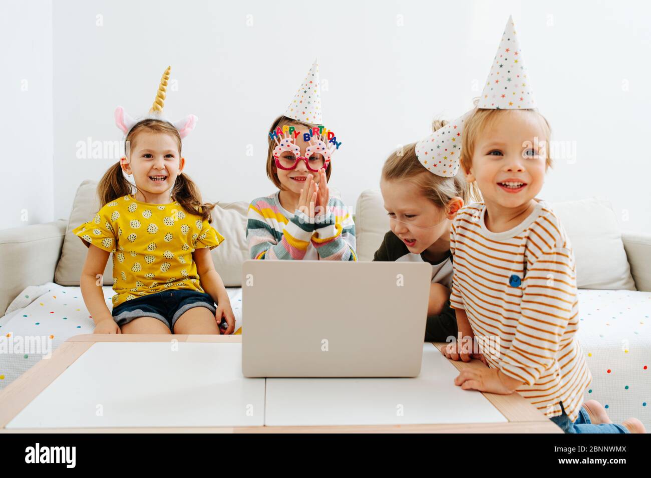 Happy kids in party hats celebrating birthday online on a quarantine at home Stock Photo