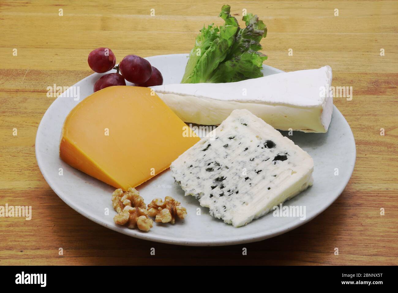 Assorted French cheese on a plate (Mimolette, Brie and blue cheese) Stock Photo