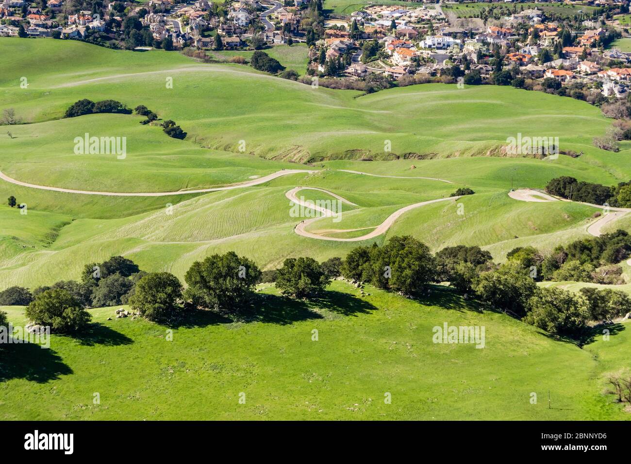 Mission Peak hiking trail on the verdant hills of South San Francisco Bay Area; residential community visible at the base of the hill; Fremont, Califo Stock Photo