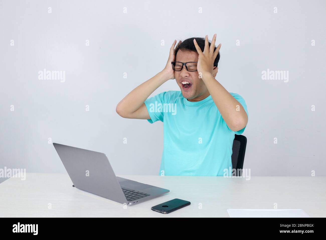 Young Asian man is Angry and Shock with laptop. Indonesian man wearing blue shirt. Stock Photo