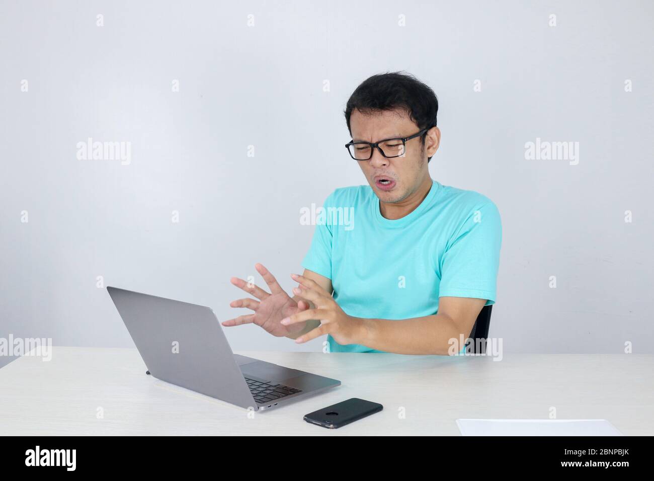 Young Asian man is Angry and Shock with laptop. Indonesian man wearing blue shirt. Stock Photo