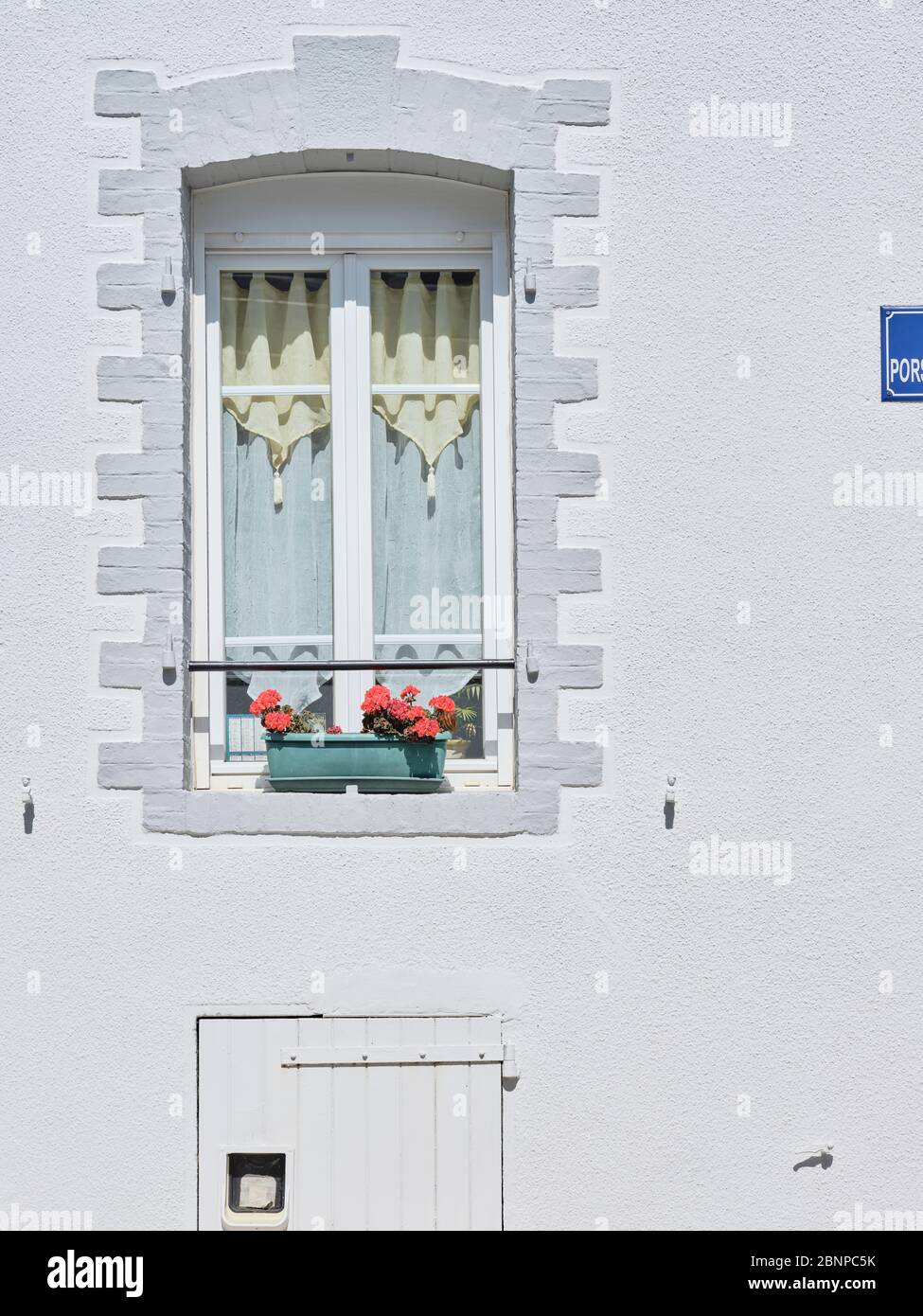 Detail view of a facade with a flower box with geraniums on the window in Brest in Brittany. Stock Photo