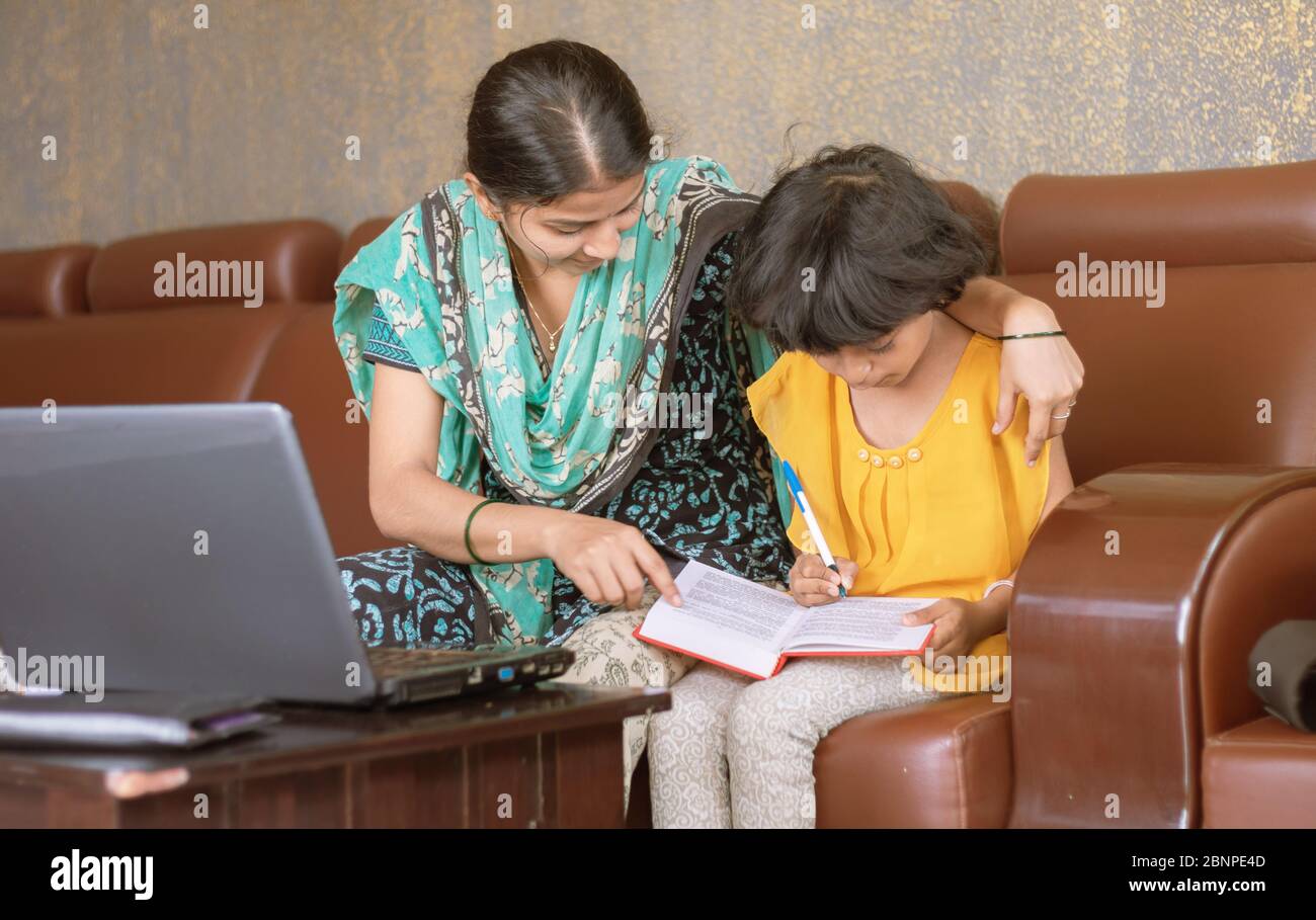 young mother teaching her child while working on laptop - concept of People Lifestyles and technology, work form home or wfh reality Stock Photo