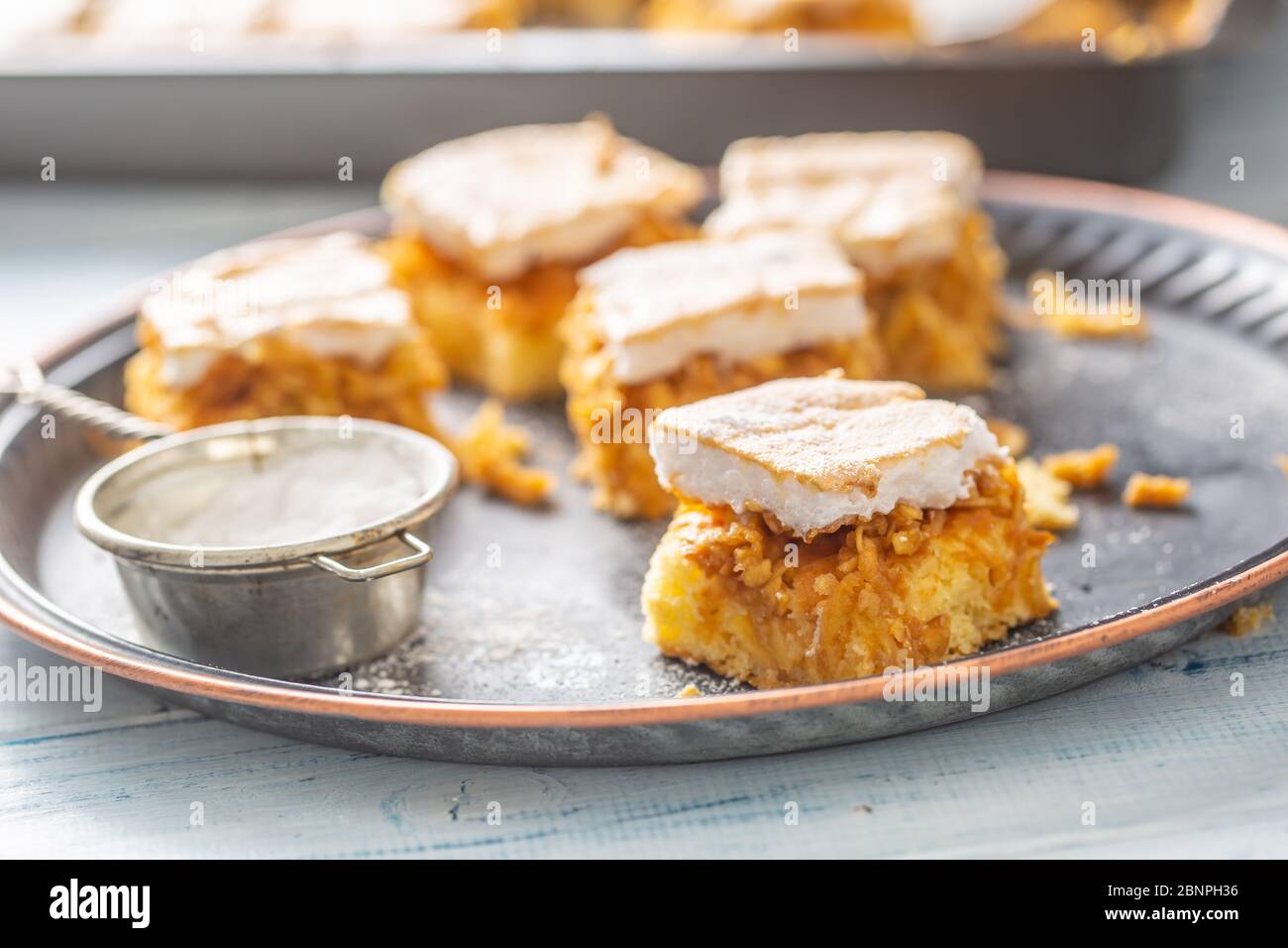 Cubes cut applie pie on a vintage tray with a sugar sieve and baking tray in the background. Stock Photo