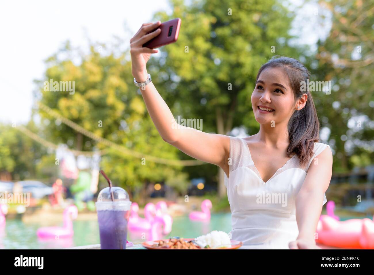 Happy young beautiful Asian woman taking selfie outdoors Stock Photo ...