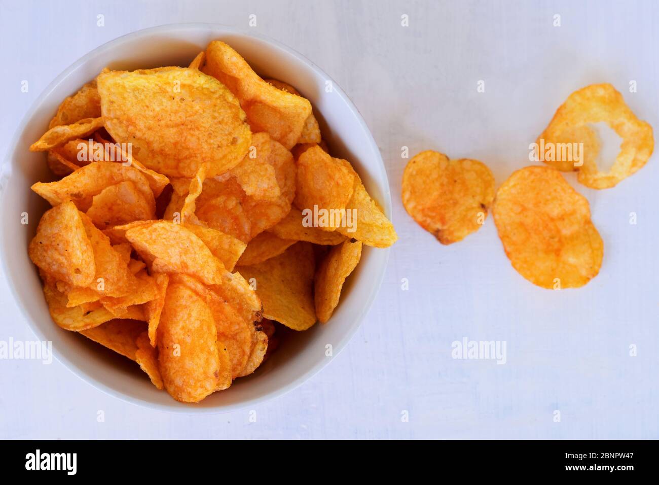 Closeup of potato chips or crisps in bowl against white background