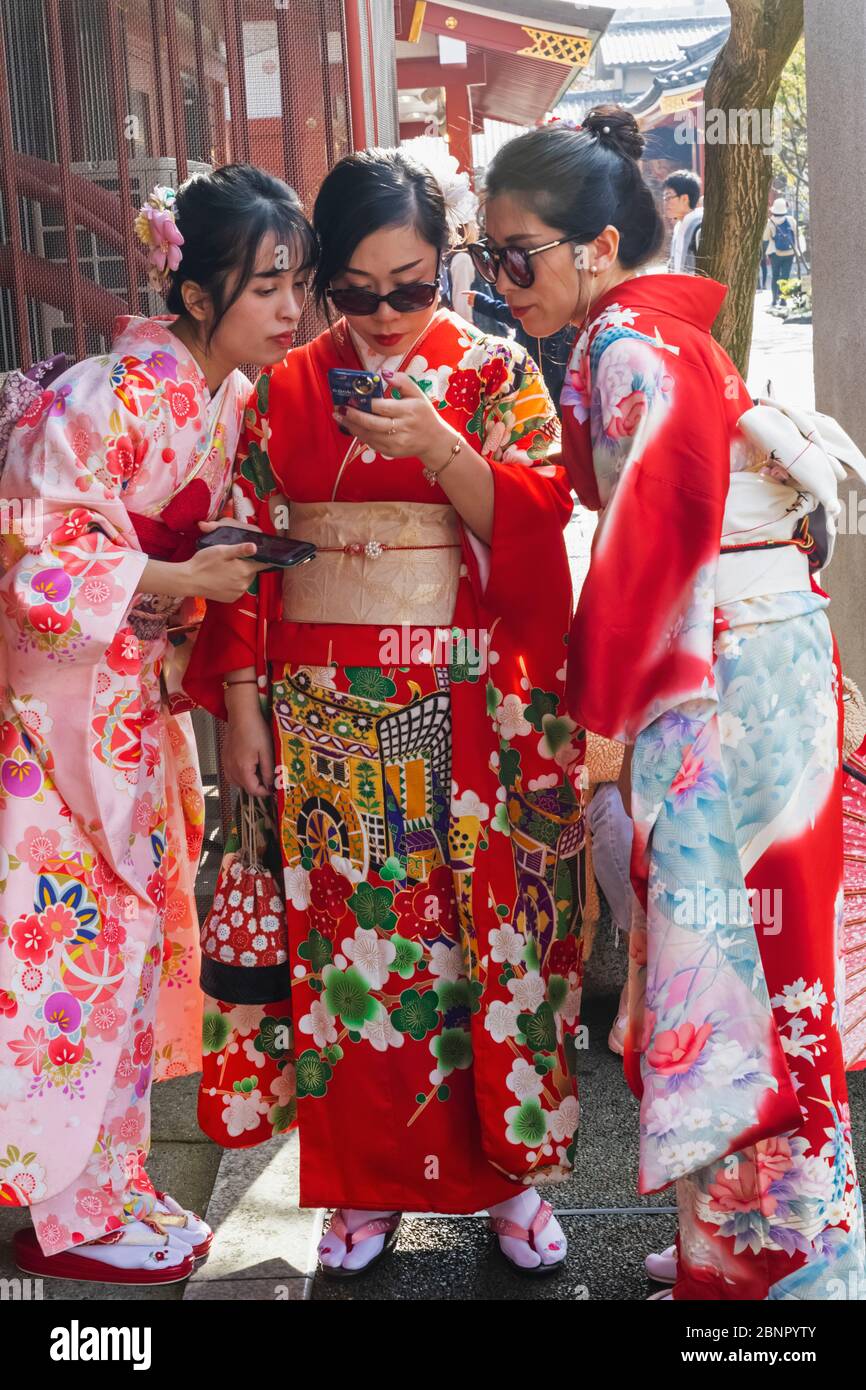 Japan, Honshu, Tokyo, Asakusa, Women in Kimono Looking at Selfie Photos on iPhone Stock Photo