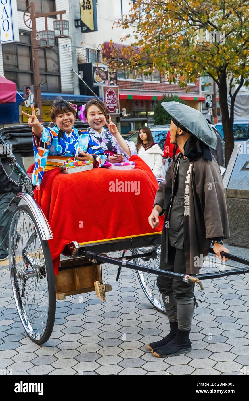 Japan, Honshu, Tokyo, Asakusa, Two Young Women Dressed in Kimono Riding in Rickshaw Stock Photo
