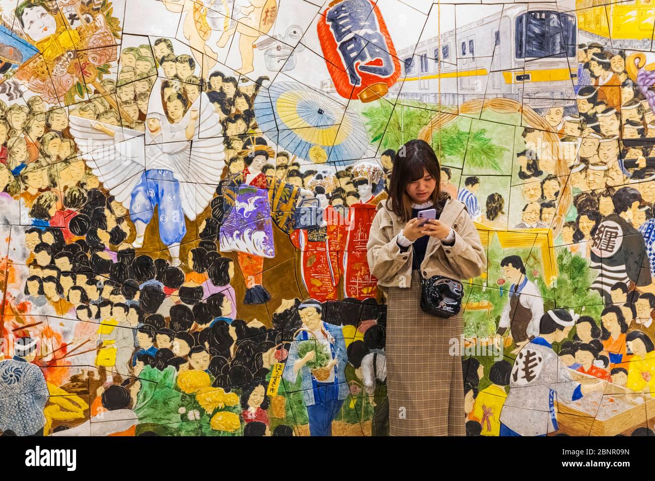 Japan, Honshu, Tokyo, Asakusa, Ginza Subway Line, Asakusa Station, Young Woman Standing in Front of Mosaic depicting Popular Festivals Stock Photo