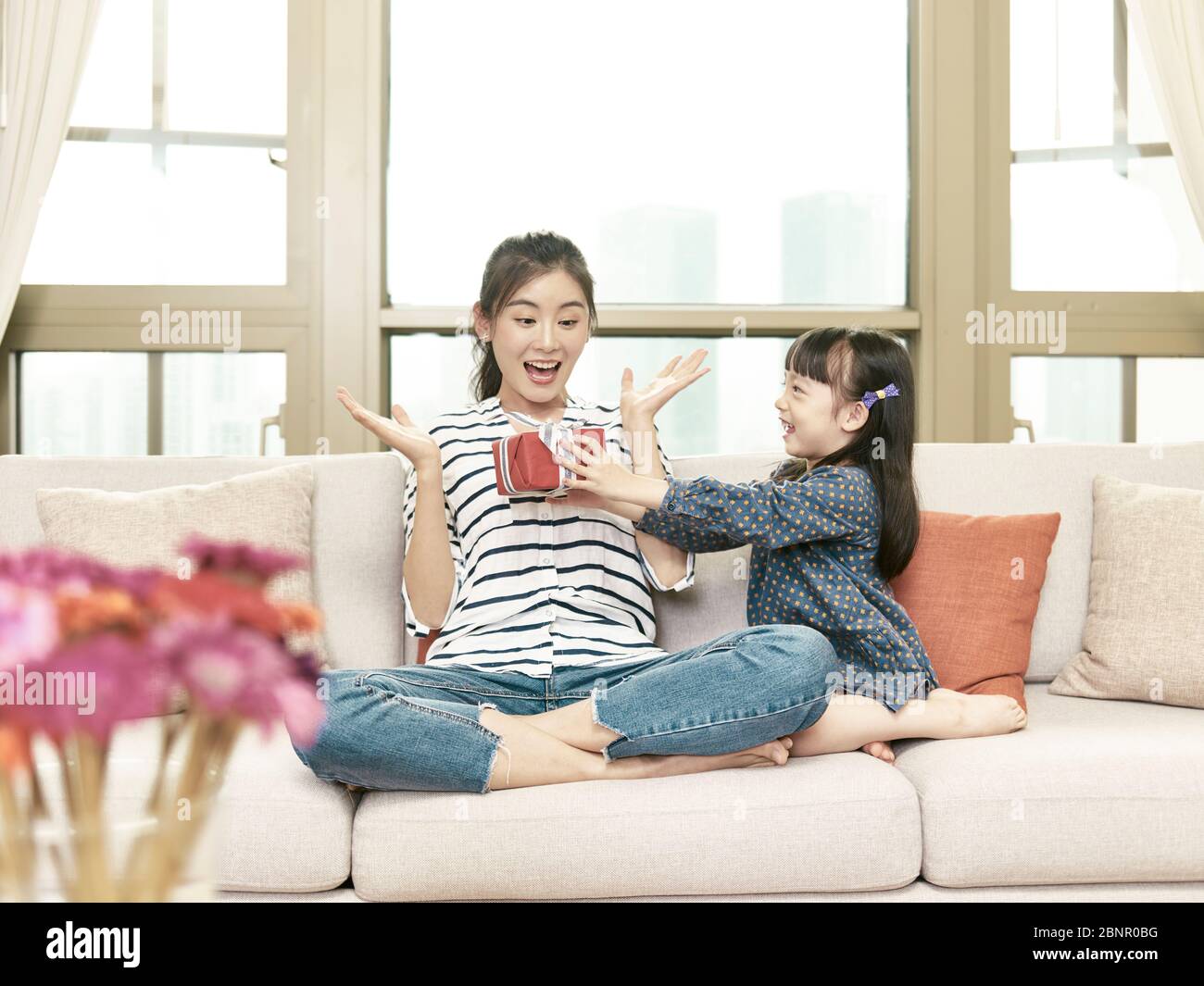 young asian mother receiving a present from daughter on birthday Stock Photo