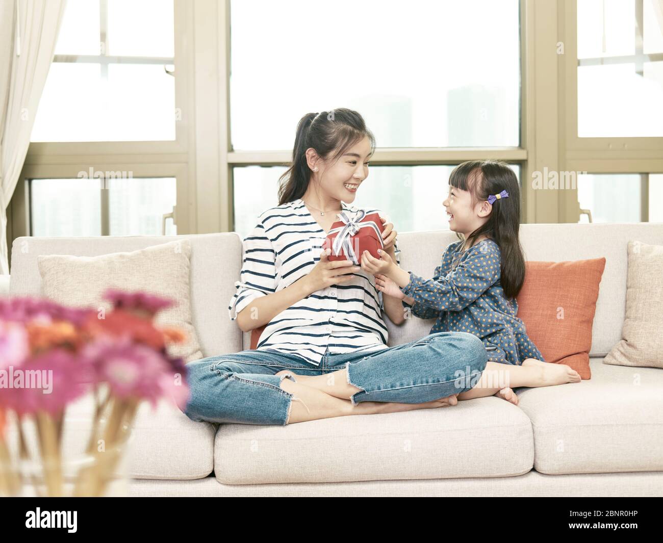young asian woman receiving a present from daughter on birthday day Stock Photo