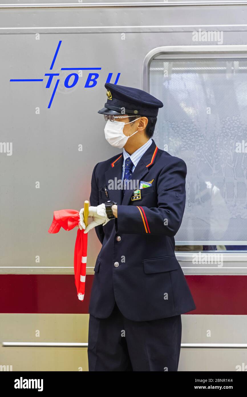 Japan, Honshu, Tokyo, Asakusa Station, Tobu Railways, Platform Guard Checking Watch for Exact Train Departure Time Stock Photo