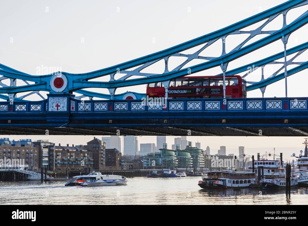 England, London, Double Decker Buses Crossing Tower Bridge with Canary Wharf Skyline in The Back at Dawn Stock Photo