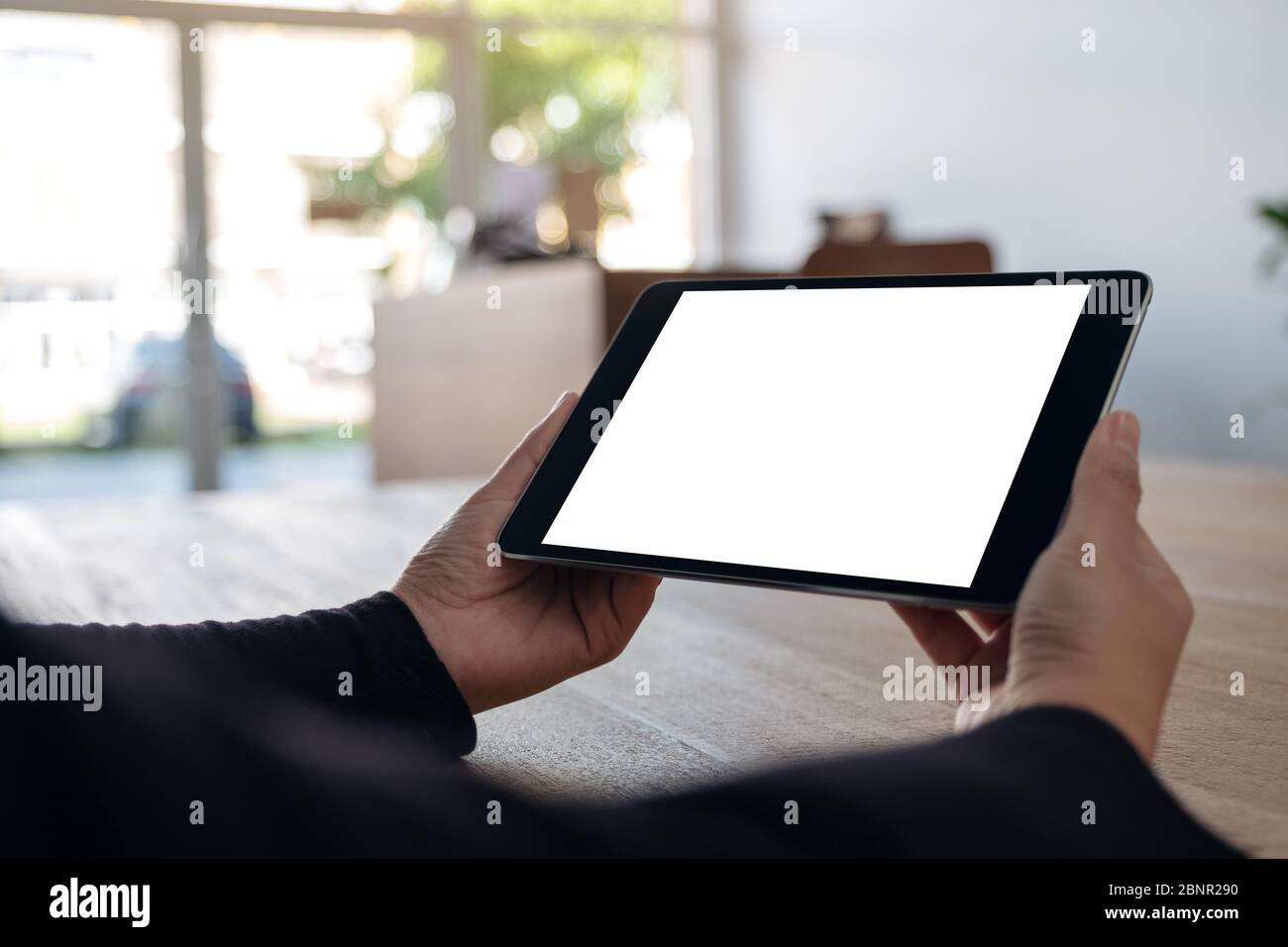 Mockup image of hands holding black tablet pc with blank white screen ...
