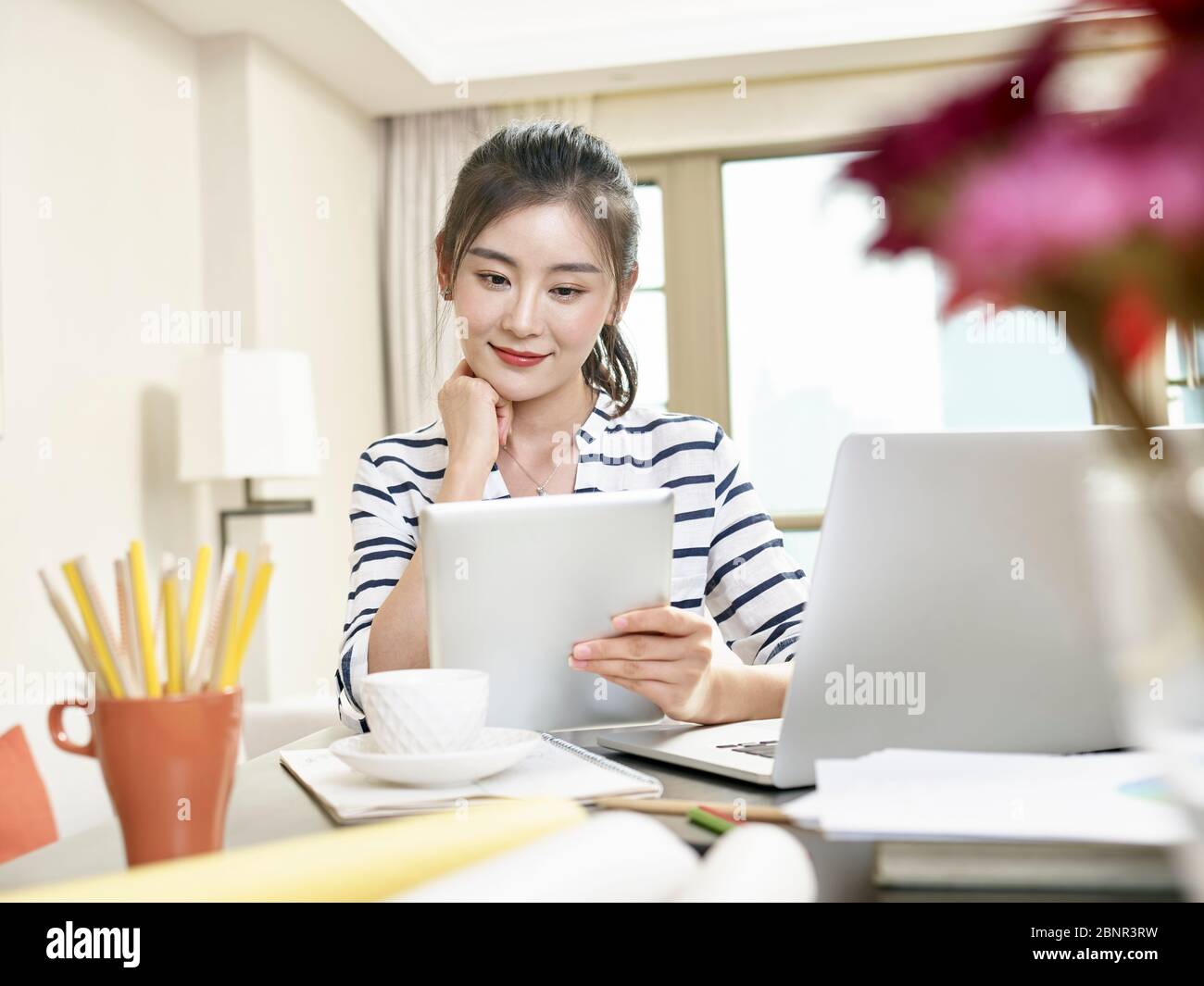 young asian business woman working at home using laptop computer and digital tablet Stock Photo